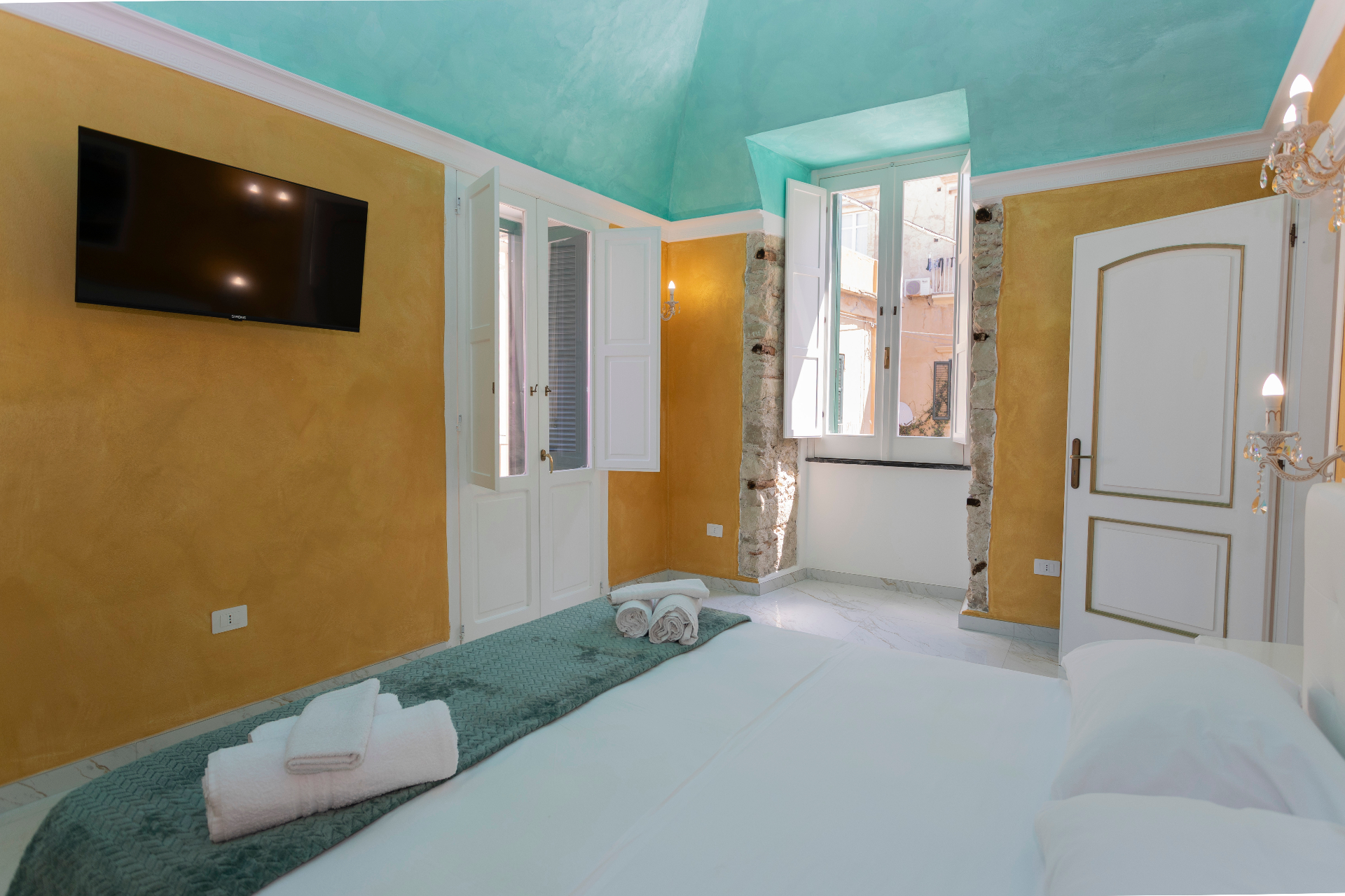 Suite Smeraldo - camera con soffitto acquamarina, TV e finestre affacciate sul centro storico