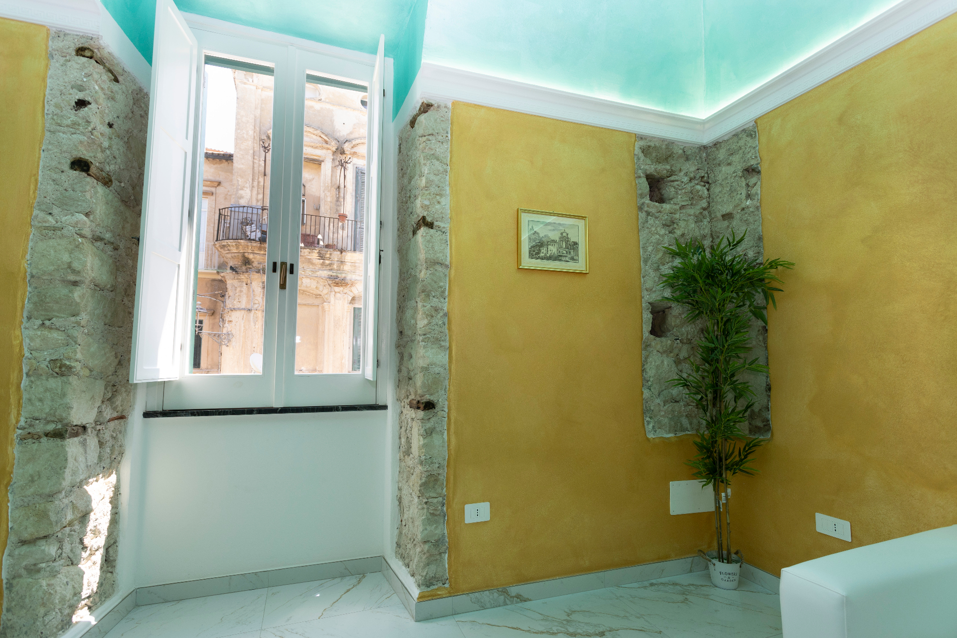 Suite Smeraldo - finestra aperta sul palazzo storico con pareti oro e dettagli in pietra