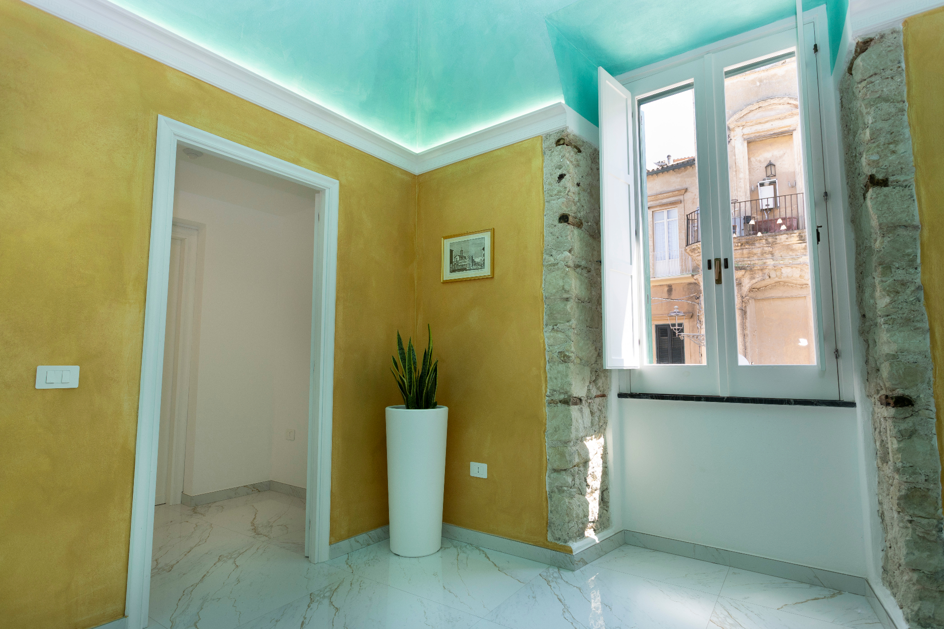 Suite Smeraldo - angolo con pietra a vista, finestra sul centro storico e soffitto acquamarina retroilluminato
