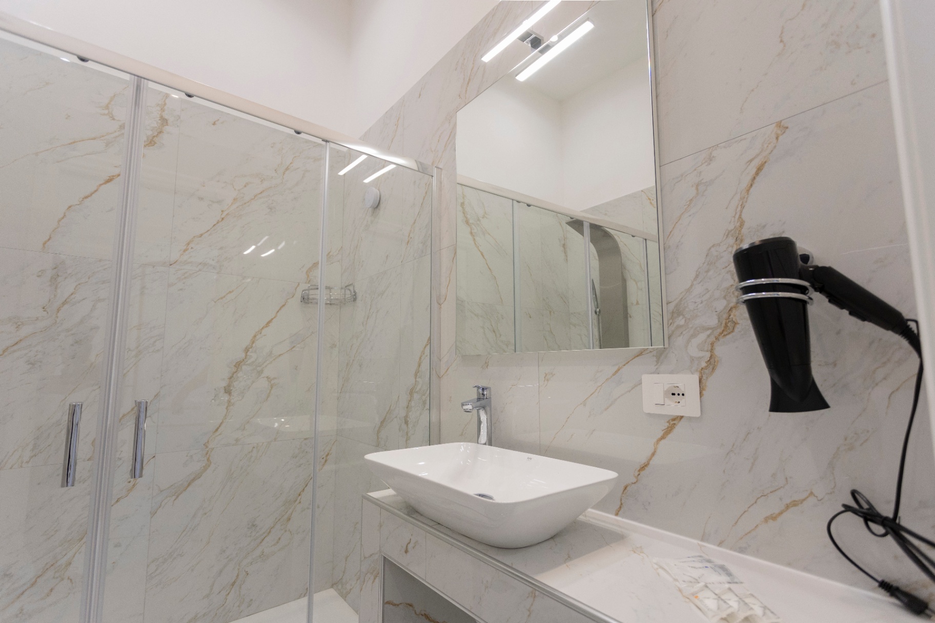 Suite Perla - bagno luminoso in marmo con lavabo da appoggio, specchio e asciugacapelli