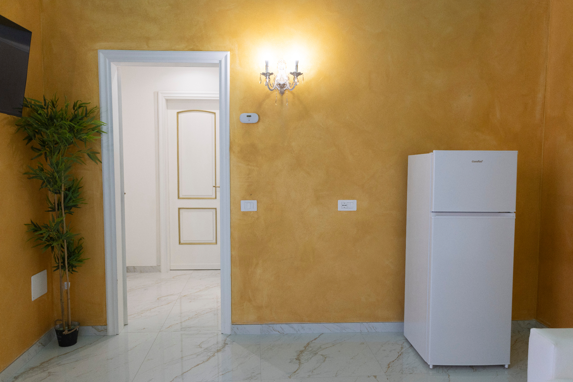 Suite Perla - angolo living con frigorifero, pareti oro satinato e accesso alla camera