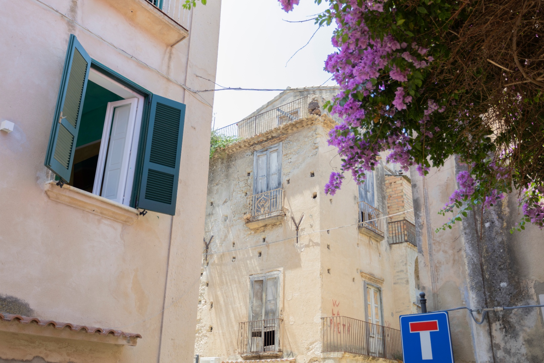 Finestra con persiane verdi e bouganville nel centro storico di Tropea