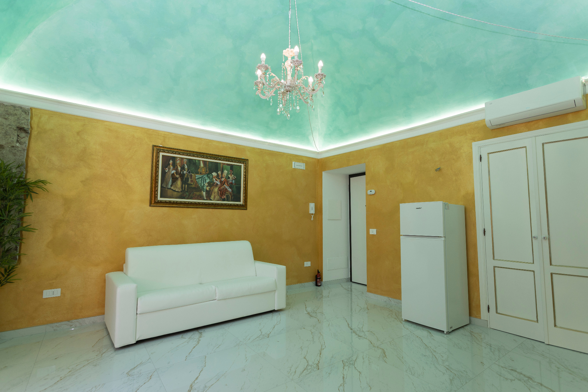 Suite Smeraldo - ampio salotto con lampadario in cristallo, soffitto acquamarina e divano bianco