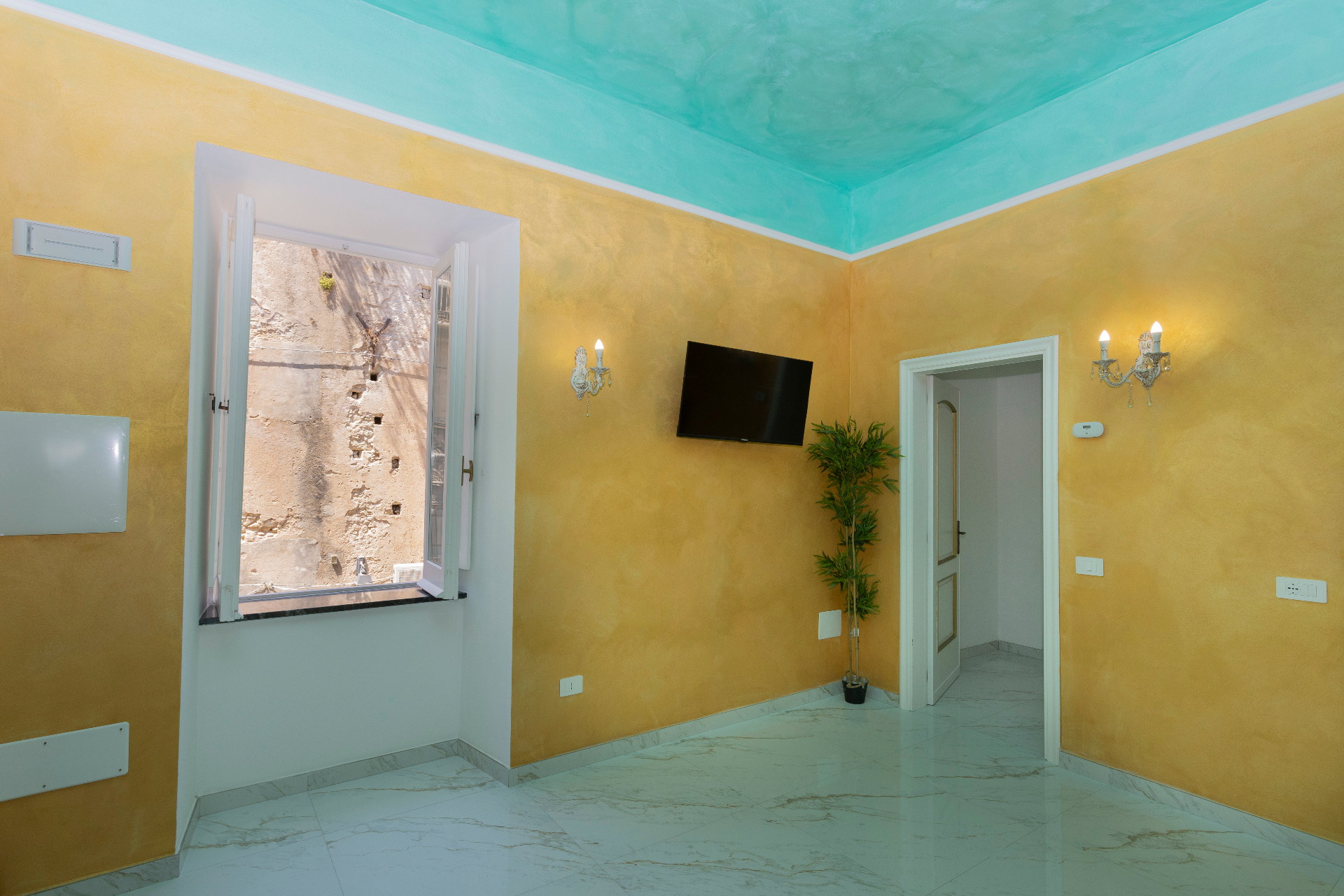 Suite Perla - soggiorno luminoso con finestra aperta, pareti oro e soffitto acquamarina