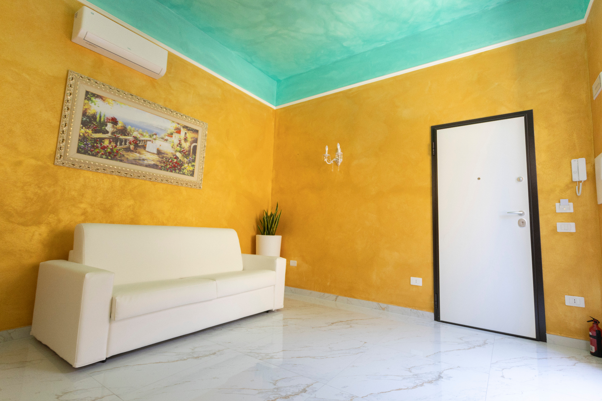 Suite Perla - salotto con divano bianco, quadro incorniciato e ingresso della suite